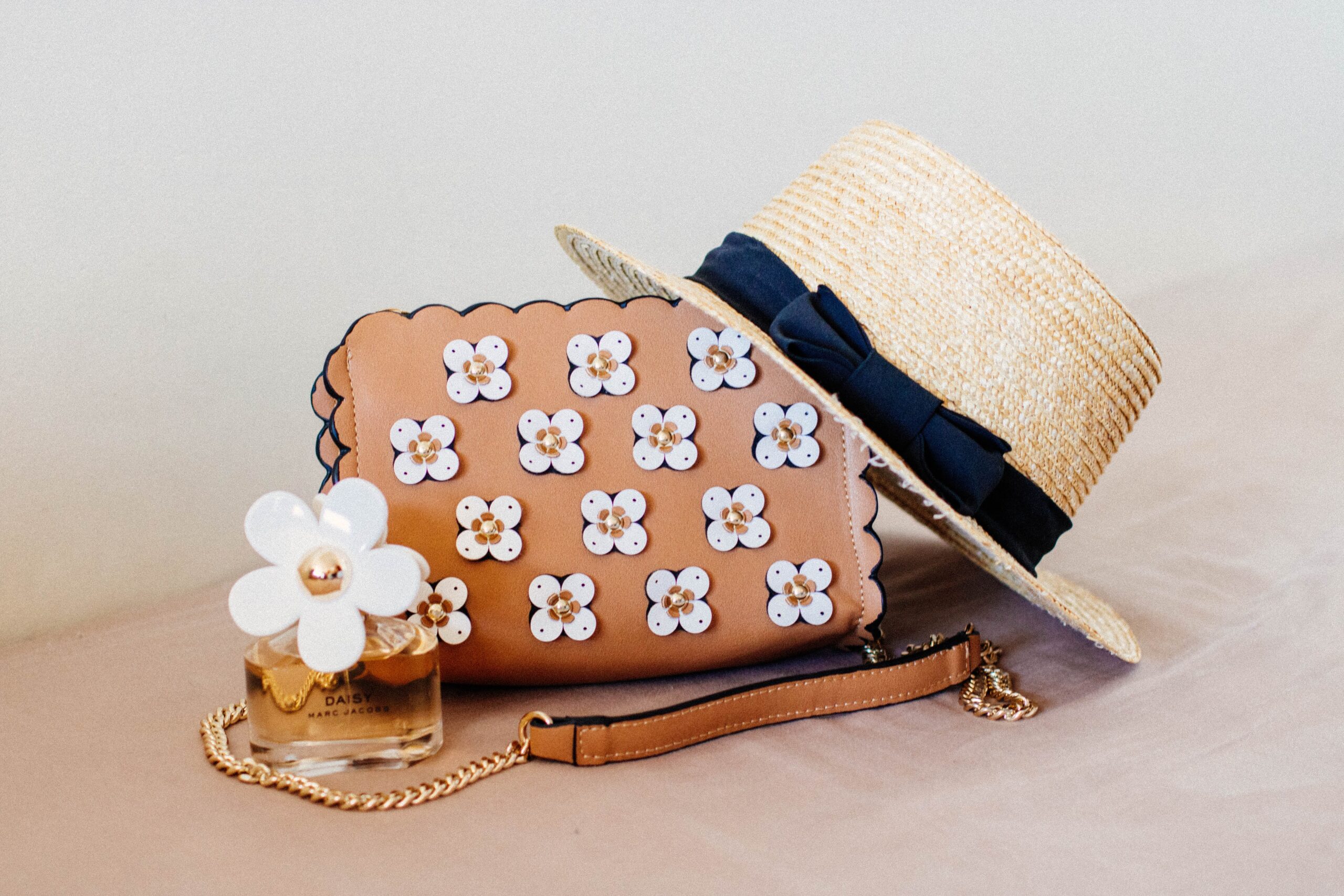 A straw hat with a black bow tied around it and a brown leather purse adorned with white flowers, both perfect accessories for a senior portrait session with Erin Daugherty Photography.